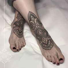 a woman's feet with hendix tattoos on them, sitting on a bed