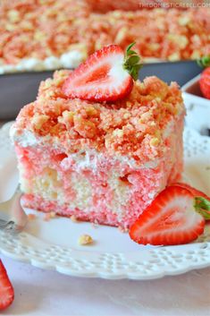 a piece of strawberry cake on a white plate with strawberries next to it and another slice in the background