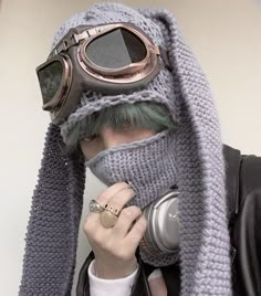 a man with green hair wearing a gray knitted hat, scarf and goggles