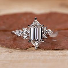 an emerald cut diamond ring on top of a leaf