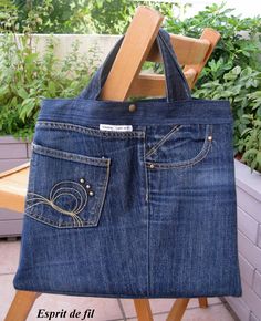 a bag made out of blue jeans sitting on top of a wooden chair next to a potted plant