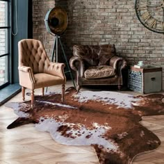 a living room with two chairs and a cowhide rug on the floor in front of a brick wall