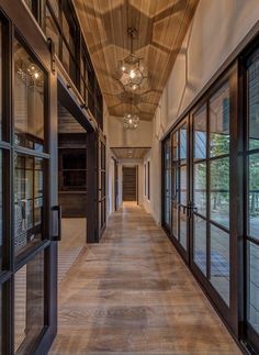 an empty hallway with large windows and wooden ceiling