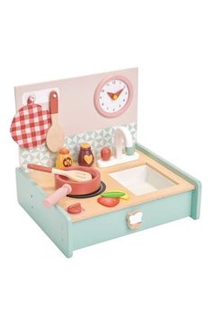 a wooden toy kitchen with a clock on the wall and various cooking utensils