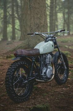 a dirt bike parked in the woods next to a tree