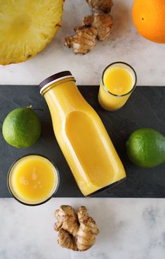 orange juice in a glass next to two lemons and ginger