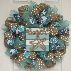 a blue and white wreath with the word beach on it's side, hanging on a door