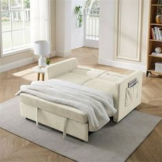 a white couch sitting on top of a rug next to a book shelf filled with books