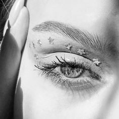 a woman's eye with stars painted on the upper part of her face and bottom half