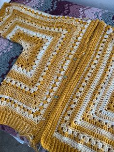 a crocheted blanket sitting on top of a bed next to a pillow and table