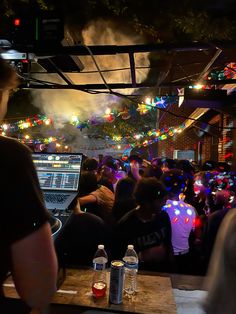 a large group of people sitting at tables in front of laptops with lights on them