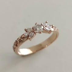 a gold ring with three diamonds on it's side, sitting on a white surface