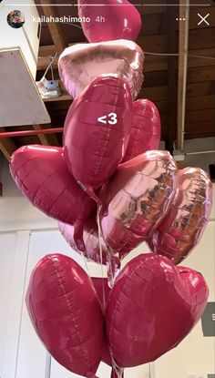 some pink heart shaped balloons are hanging from a pole in a room with white tile flooring