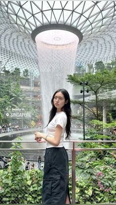 a woman standing in front of a fountain at the gardens by the bay, singapore