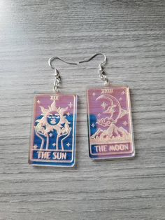 This listing is for one pair of iridescent The Sun and The Moon mismatched acrylic tarot card earrings. The engraved areas shimmer in the light! The iridescent acrylic sometimes has a slight bubbling in spots. I do my best to avoid this and it's usually barely noticeable unless up close! Doesn't take away from the shimmer though! These are about 2 inches and very lightweight. These are laser cut acrylic! Jewelry hardware is hypo allergenic stainless steel. Leverbacks are available upon request! Tarot Card Earrings, Laser Engraving Acrylic, Tarot Earrings, Acrylic Earrings Laser Cut, Laser Jewelry, Card Earrings, Witchy Earrings, Moon Tarot Card, Laser Engraved Acrylic