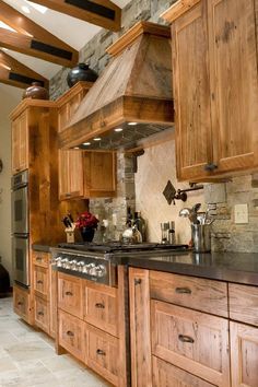 a kitchen with wooden cabinets and black counter tops, an oven and stove hood in the center