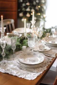 the table is set for christmas dinner with white plates and silverware