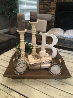 a tray with candles, books and other items on it in front of a fireplace