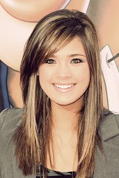 a young woman with long hair and bangs smiling at the camera in front of a movie poster