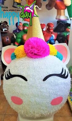 a white stuffed animal with a pink flower on it's head and a happy birthday card in the background