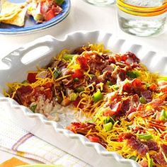 a casserole dish with bacon, cheese and other toppings on a table