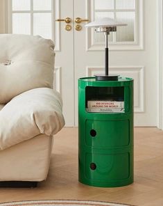 a green trash can sitting on top of a hard wood floor