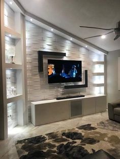 a living room filled with furniture and a flat screen tv mounted on the wall above it