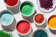 six bowls filled with different colored powders on top of a white countertop next to each other