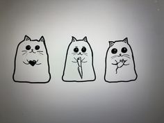 three bags with cats drawn on them sitting in front of a computer screen, one is holding a flower and the other has a heart