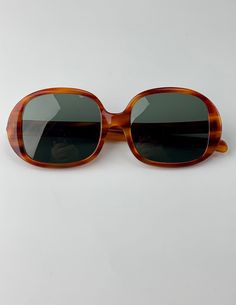 "Vintage 1960'S Ray-Ban Oval Sunglasses in a tortoise colored frame. These Optical Quality frames have the original glass lenses in a smokey green color.  On the inside of one stem is etched \"B & L Ray-Ban USA\" and on the other side is etched \"Kilaine\" These sunglasses are Used and in EXCELLENT VINTAGE CONDITION. there are a few very minor scratches, otherwise, no issues to mention. The hinges are in excellent working order, and the frames are not warped or crooked. *For a good fit, compare Vintage Tortoiseshell Sunglasses, Retro Oval Brown Sunglasses, Vintage Tortoiseshell Sunglasses With Gradient Lenses, Retro Brown Oval Sunglasses, Vintage Oval Sunglasses For Formal Occasions, Vintage Brown Sunglasses For Formal Occasions, Vintage Brown Glass Sunglasses, Vintage Ray Ban, Timeless Sunglasses