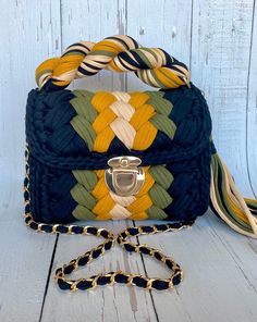 a blue, yellow and green handbag sitting on top of a white wooden floor