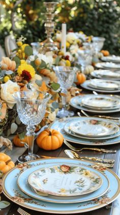 a table set with plates, silverware and pumpkins