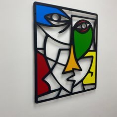 a colorful abstract painting on the wall next to a white wall with a black frame