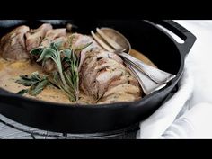 a pan filled with meat covered in sauce and garnished with herbs