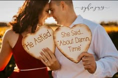 a man and woman holding two heart shaped signs with the words he asked she said about damn time