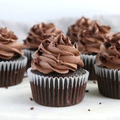 chocolate cupcakes with frosting on top sitting on a white cake platter