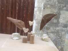 three birds are sitting on top of some rocks and wood sticks in front of a stone wall