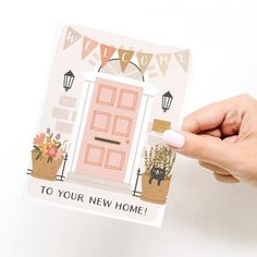 a hand holding up a card with a pink door and welcome to your new home