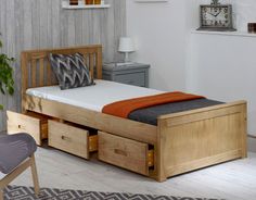 a bed with two drawers underneath it in a room next to a table and chair