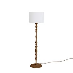 a wooden floor lamp with a white shade on the base and a cord attached to it