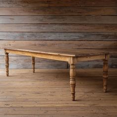 an old wooden table sitting on top of a hard wood floor next to a wall