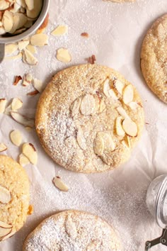 almond cookies with powdered sugar and spoons on the table next to them,