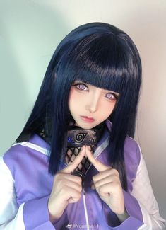 a woman with black hair and blue eyes holding a cell phone up to her face