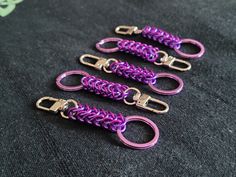 four purple and gold chainmails on a black surface