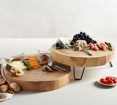 two wooden trays with different types of food on them, one holding cheese and the other serving platter