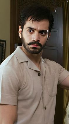 a man with a beard and mustache standing in front of a mirror