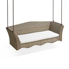 a wicker swing with cushions hanging from it