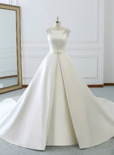 a white wedding dress on display in front of a mirror