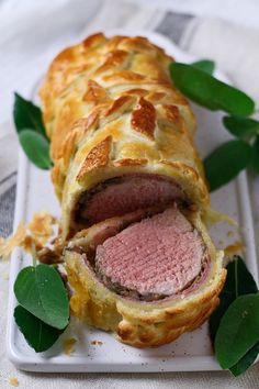 a meat and cheese pastry on a plate with green leaves around the edges, ready to be eaten