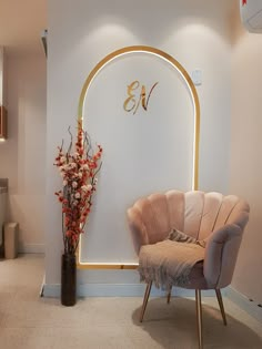 a chair and vase with flowers in front of a wall that has the initials on it